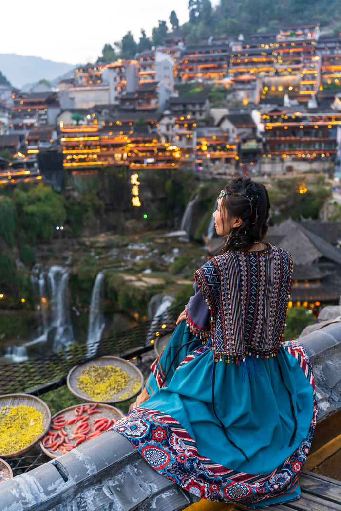Chica china mirando el horizonte en pueblo colorido chino con cascadas de fondo