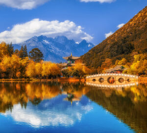Paisaje boscoso con montañas a lo lejos y un lago y puente en Yunnan, China