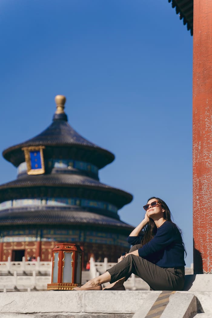 Mujer turista con gafas oscuras posando en un templo en Beijing